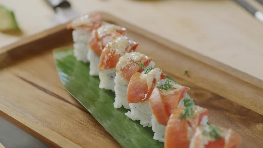A view of a person putting some sushi on a plate