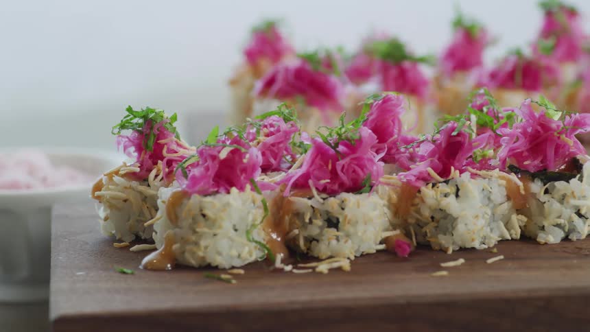 Sushigarnished and decorated sits on wooden blocks near white bowl