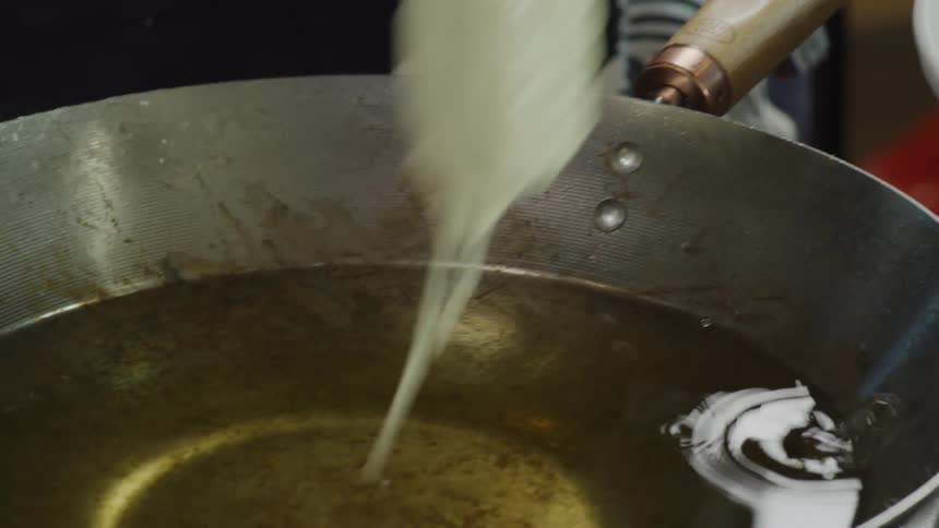 Person batters and fries tempura coated vegetables in hot boiling oil