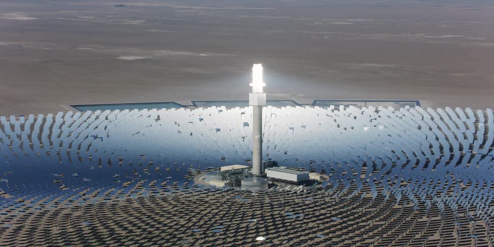 Aerial view of the bright top of a tower in the middle of a solar energy farm in the desert