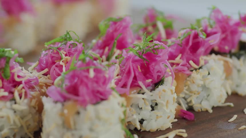 Pieces of sushi on a cutting board on a table in a room with a wall in the background