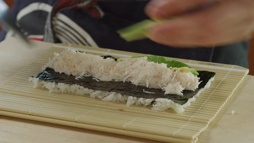 Cook slicing avocado with a sharp kitchen knife while preparing sushi