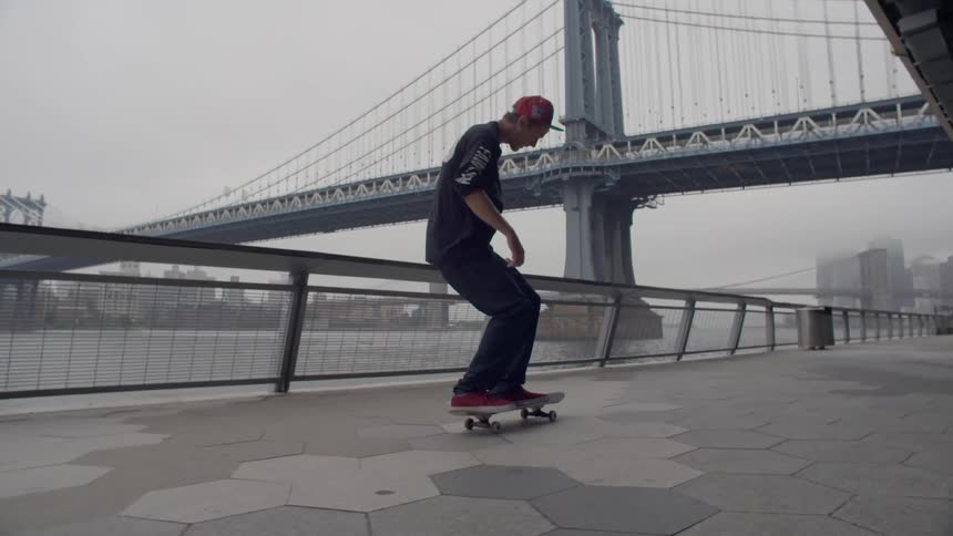 A boy skateboards next to a river