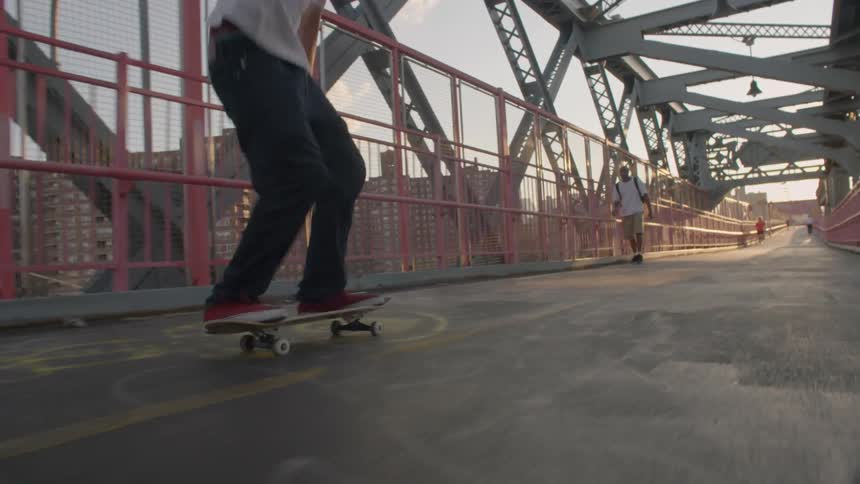 A man rides a skateboard and does a jump on a bridge
