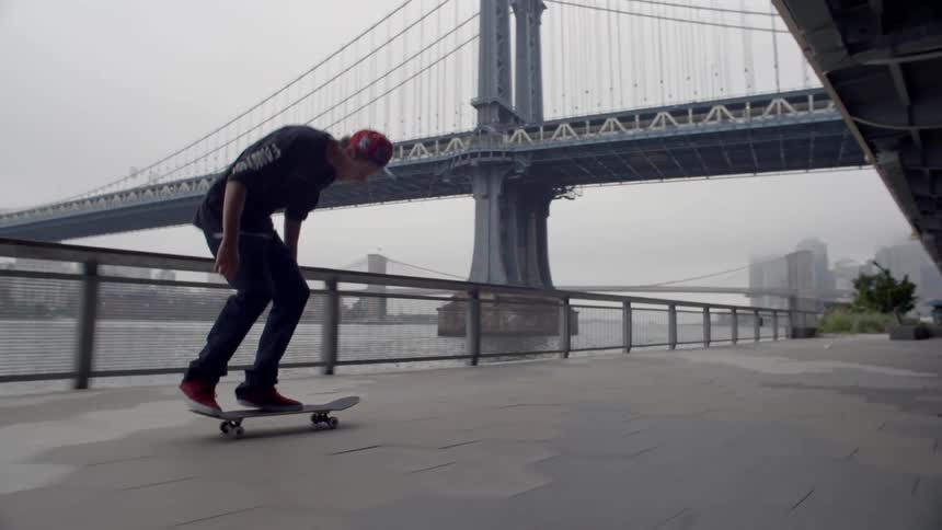 A man skateboards near a bridge