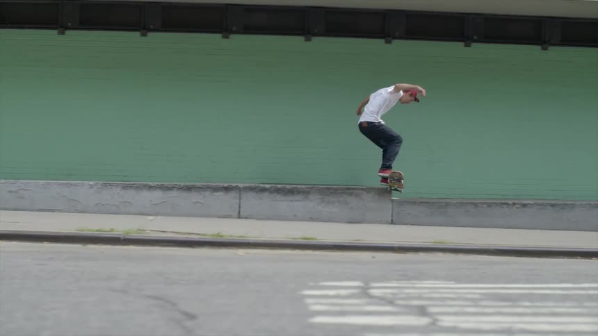 A person in a white shirt skateboards down the road