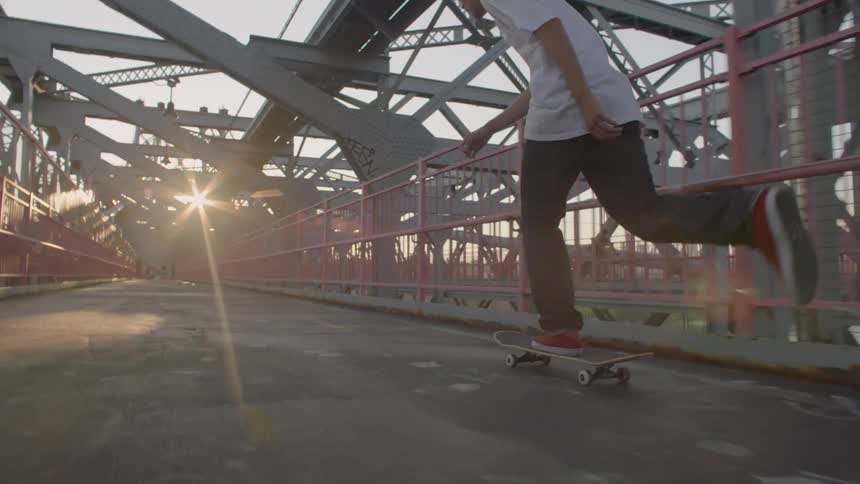 A man in white skateboards on a bridge