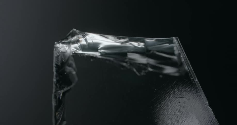 A close up of a grey shard of glass with a moving light and reflections