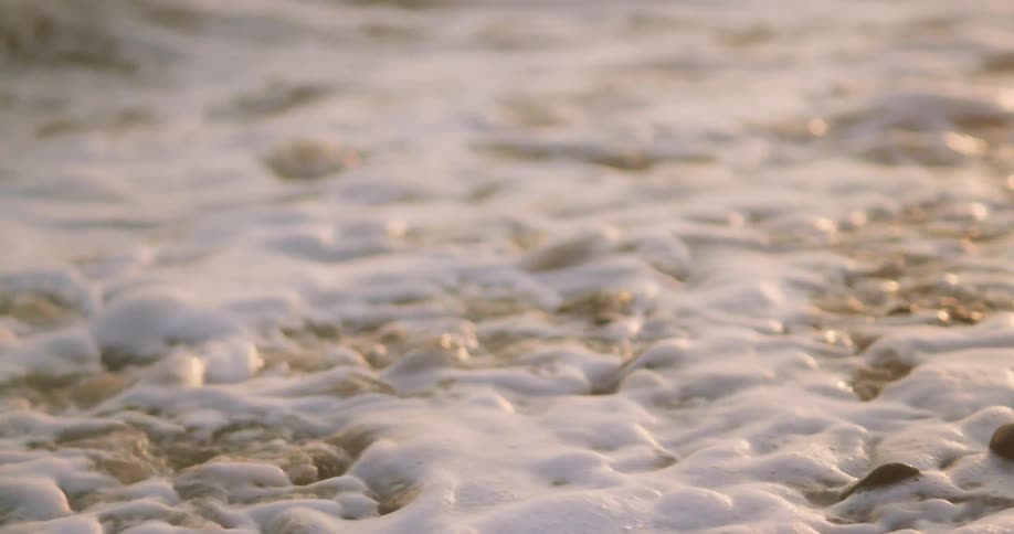 A beach with stones and pebbles with waves of water washing over it