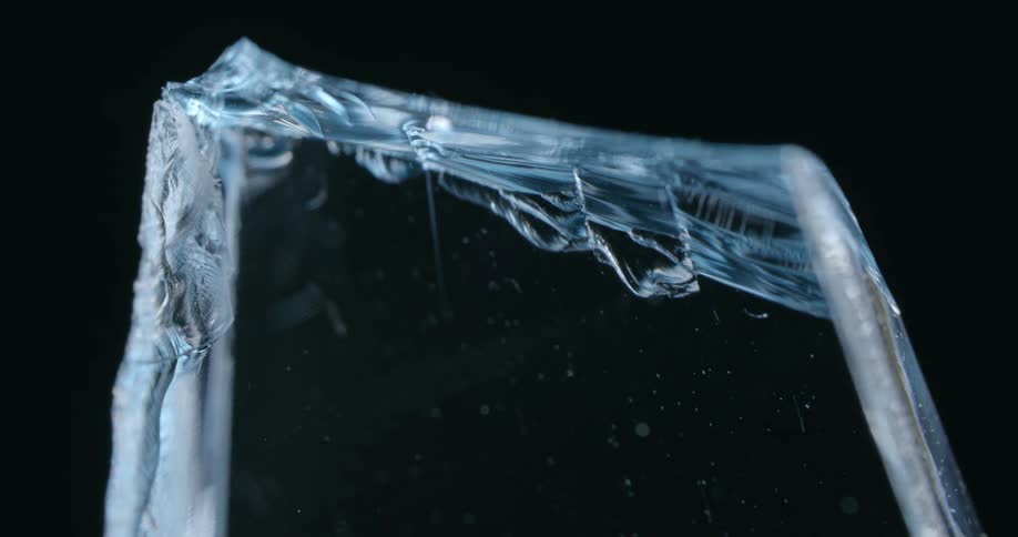 A close up of a blue shard of glass with light reflecting off the surface