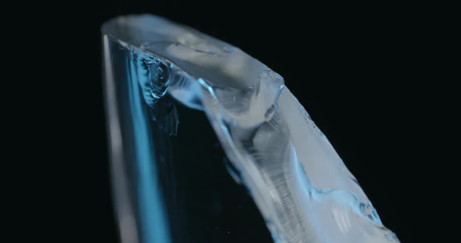 As light fades translucent rough edged piece with small nick turns blue against black background