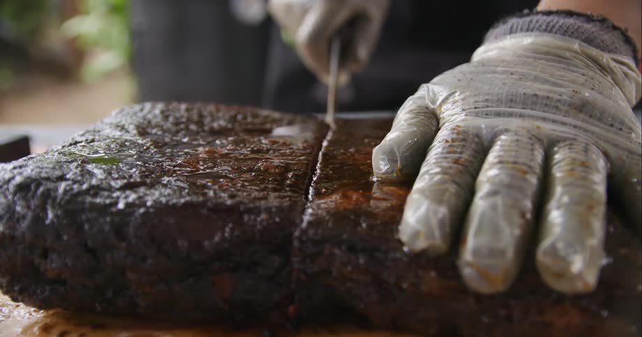 A person cutting a piece of meat in half with a knife