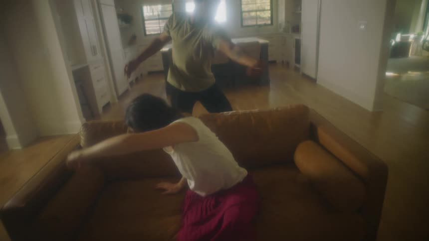 Young couple dancing around furniture in the living room at home