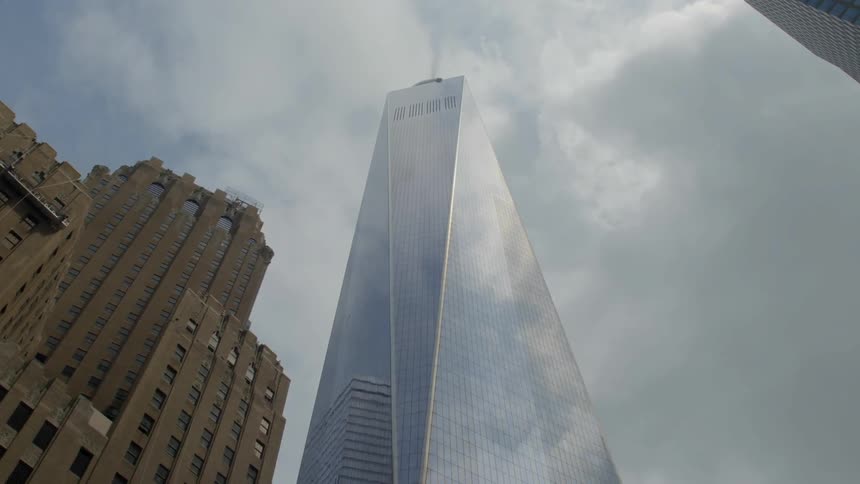 A tall glass building stands out against a cloudy sky