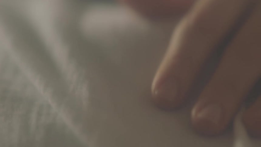 The fingers on a womans hand resting on white material