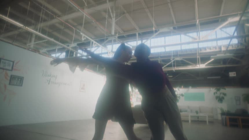 Couple of young woman dancing together inside a warehouse