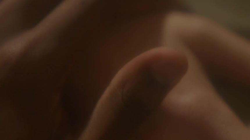 A man caresses his wifes hand with his thumb