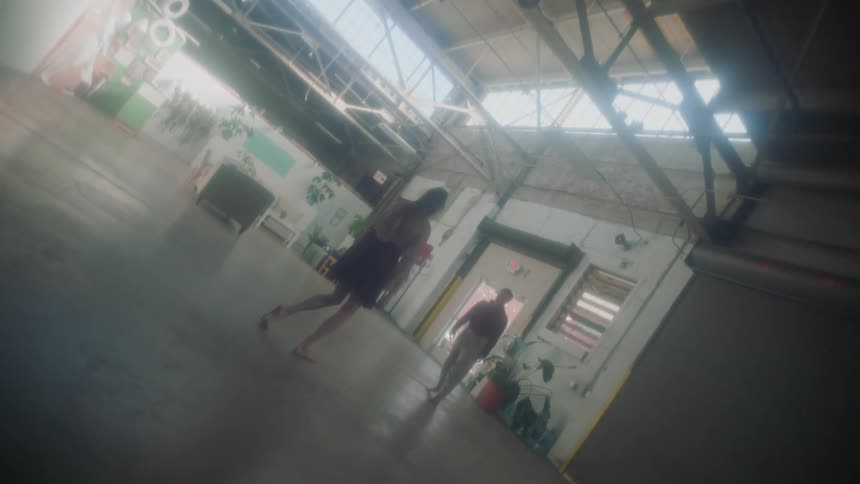 Two women dancing in a garage with a wall and doors in the background