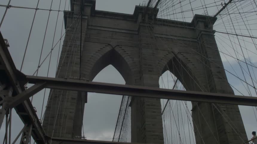 People are walking over a large bridge on a cloudy day