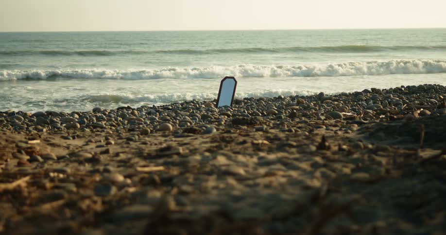 A mirror is sticking up in the sand on the beach