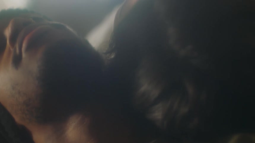 Relaxed young couple rest their heads together inside a dimly lit room