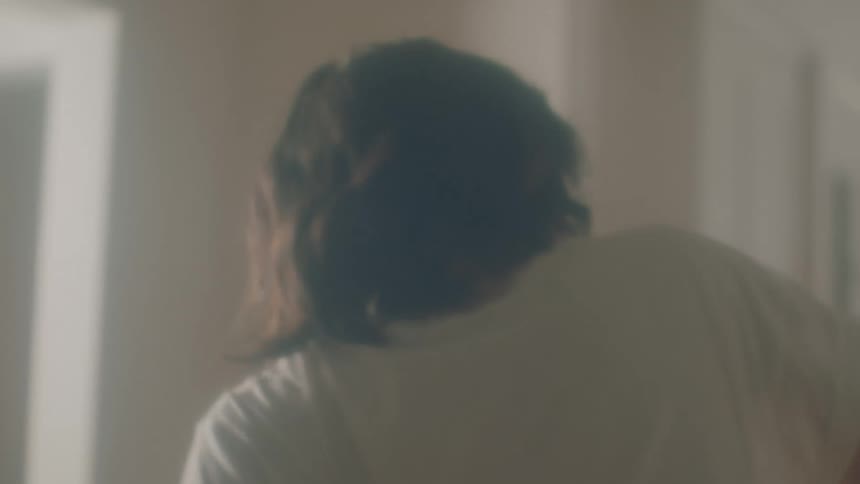 A woman does a slow modern dance around her living room