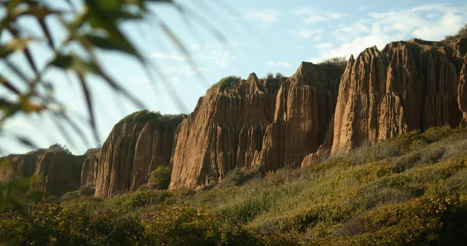 A landscape with hills and cliffs with the sky and clouds in the background