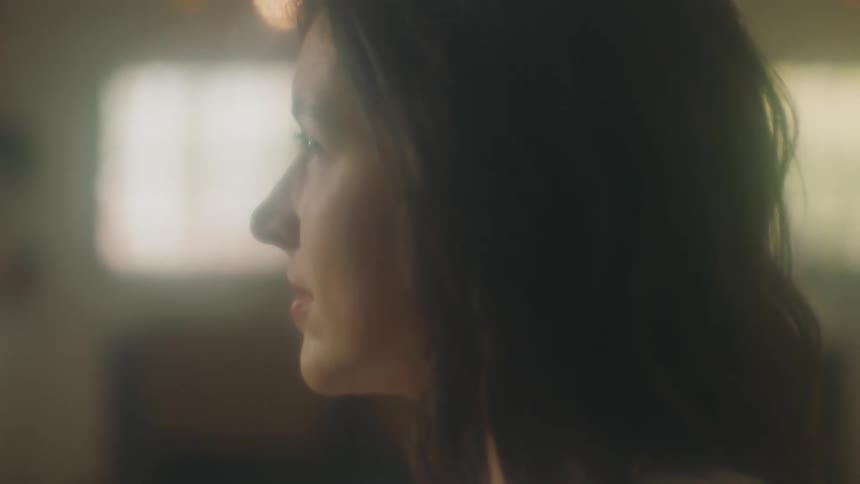 A woman in a room with a wall in the background
