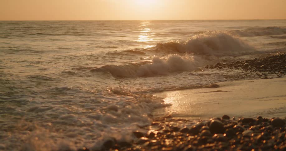 Small ocean waves gently crashing on the rocks in the coast at sunset