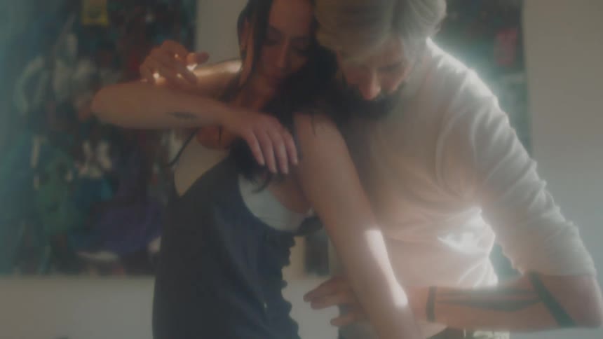 A man twirls a woman around as they dance at home