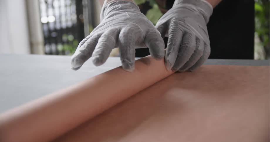 Chef wearing latex gloves unrolling film over a table