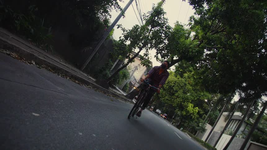 A man rides his bicycle down a side street in a neighborhood