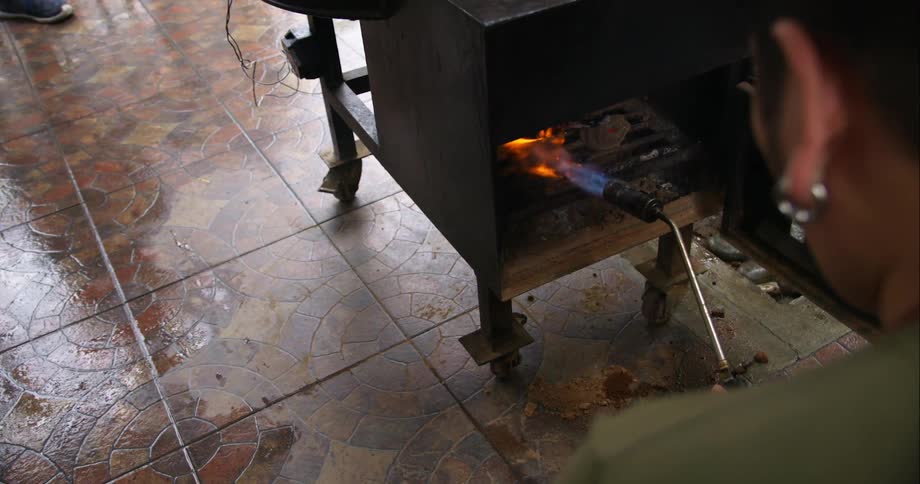 A person lighting a stove in the middle of the day