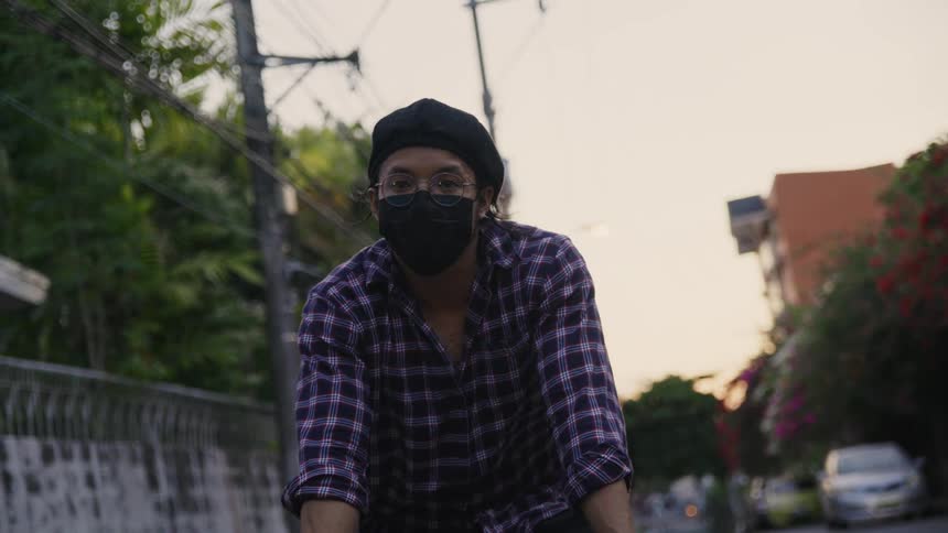 A man wears a face mask while riding his bicycle down a quiet city street