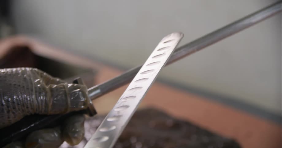 Chef sharpening a kitchen knife with an steel honing rod before cutting meat