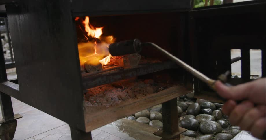 A cooker being prepared with wood and a torch