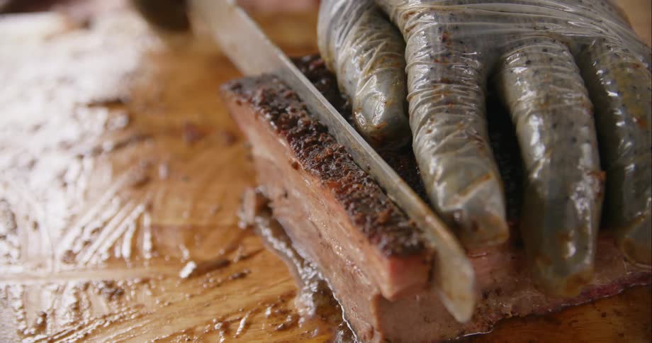 A person cutting a piece of meat with a knife