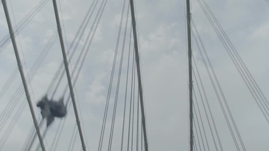 View of bridge cables and a cloudy sky while travelling