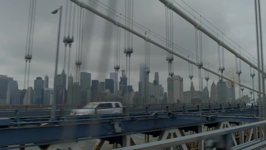 Cars driving on a bridge in front of a city