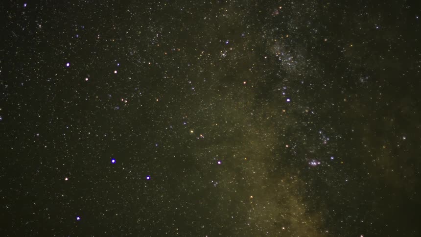 Lights streak across a night sky filled with stars