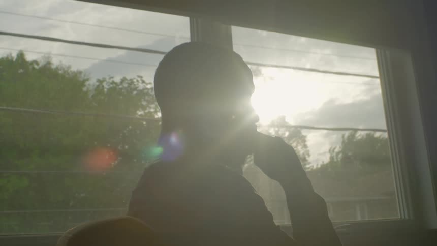 Man sitting in chair is silhouetted against the sun