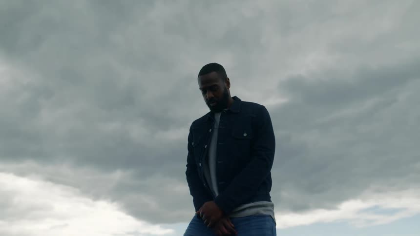 A man is distracted and turns around while standing and praying in a field