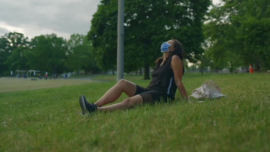 Young woman wearing sports clothes sitting on the grass in a park at morning