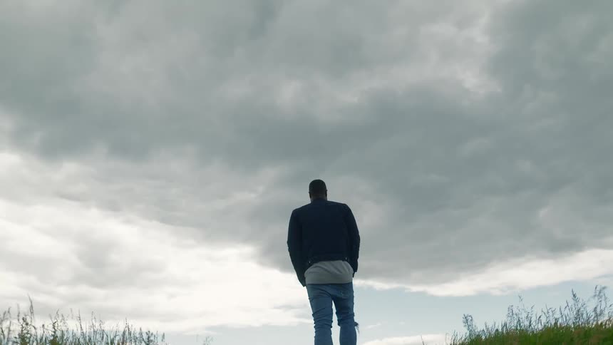 A man walks through a grassy field and looks around