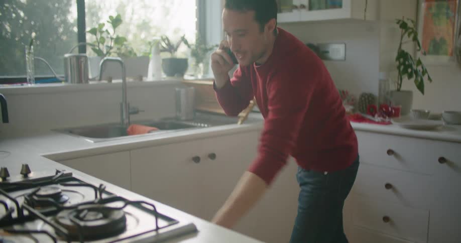 A man talks on his cell phone and looks in to his oven