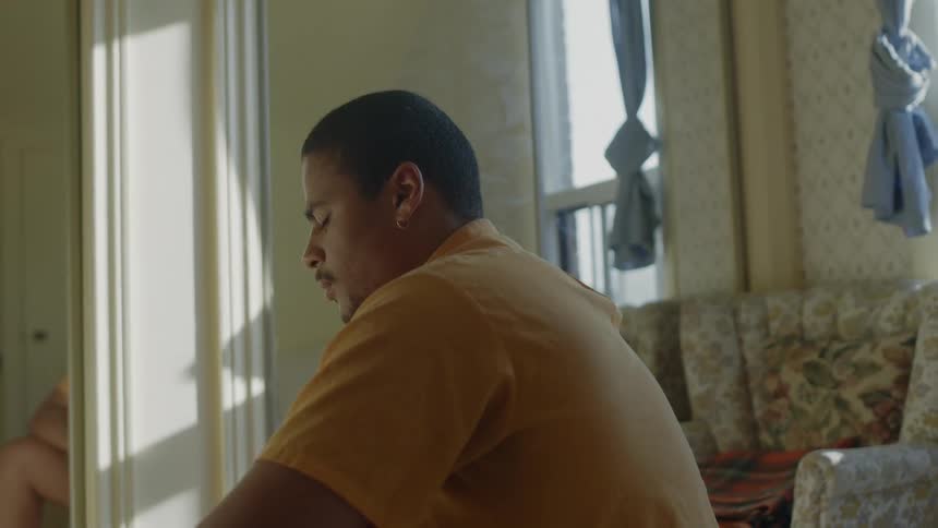 A man sits at home with sunlight shining through the windows