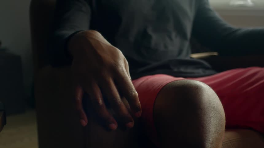 A person in a room sitting on a couch next to a table with a wall in the background