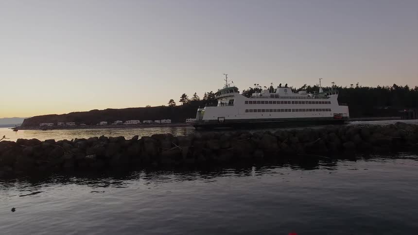 A large yacht moves in the water at sunset