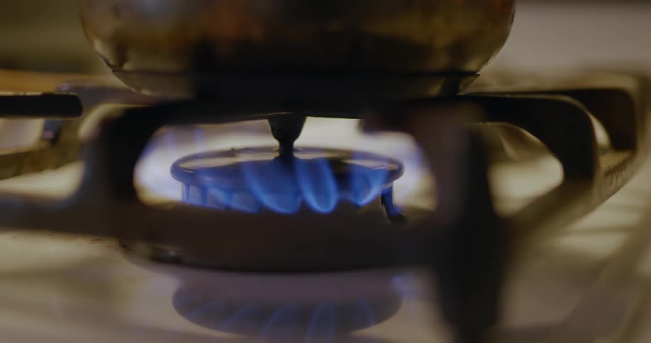 A pot is placed on a burner and the gas flame turned on and adjusted