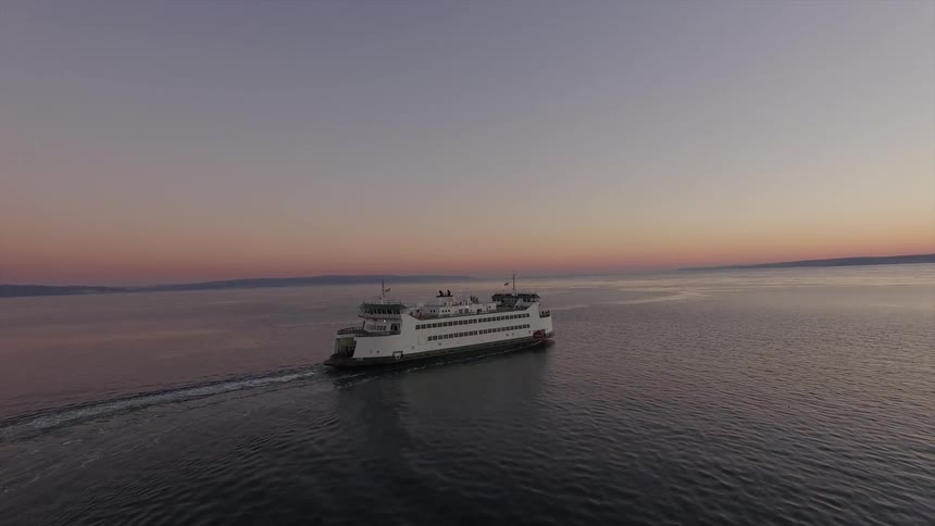 A ferry boat moves across a bay at sunset